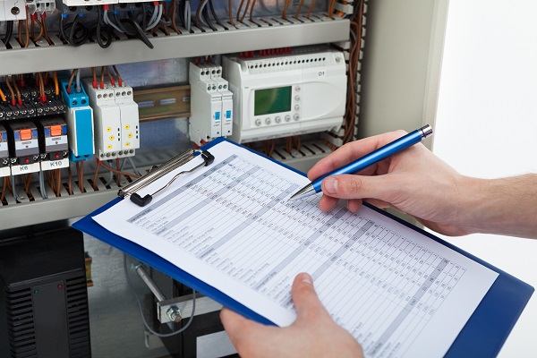 Electrician Holding Clipboard While Examining Fusebox